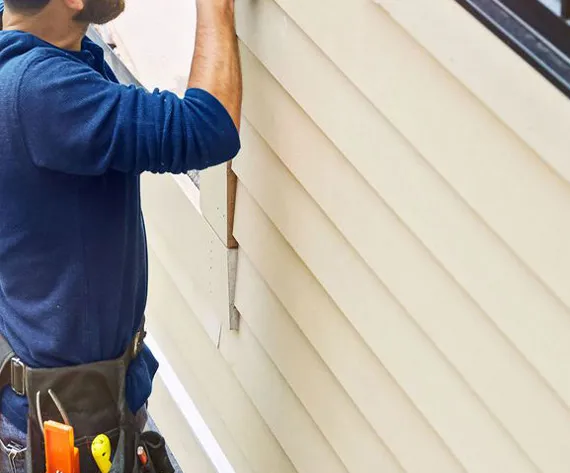 A man installing siding on a house, adding a touch of beauty and protection to the home's exterior.
